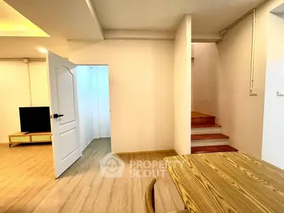 Spacious modern interior with wooden flooring and open layout, featuring a staircase and stylish furniture.