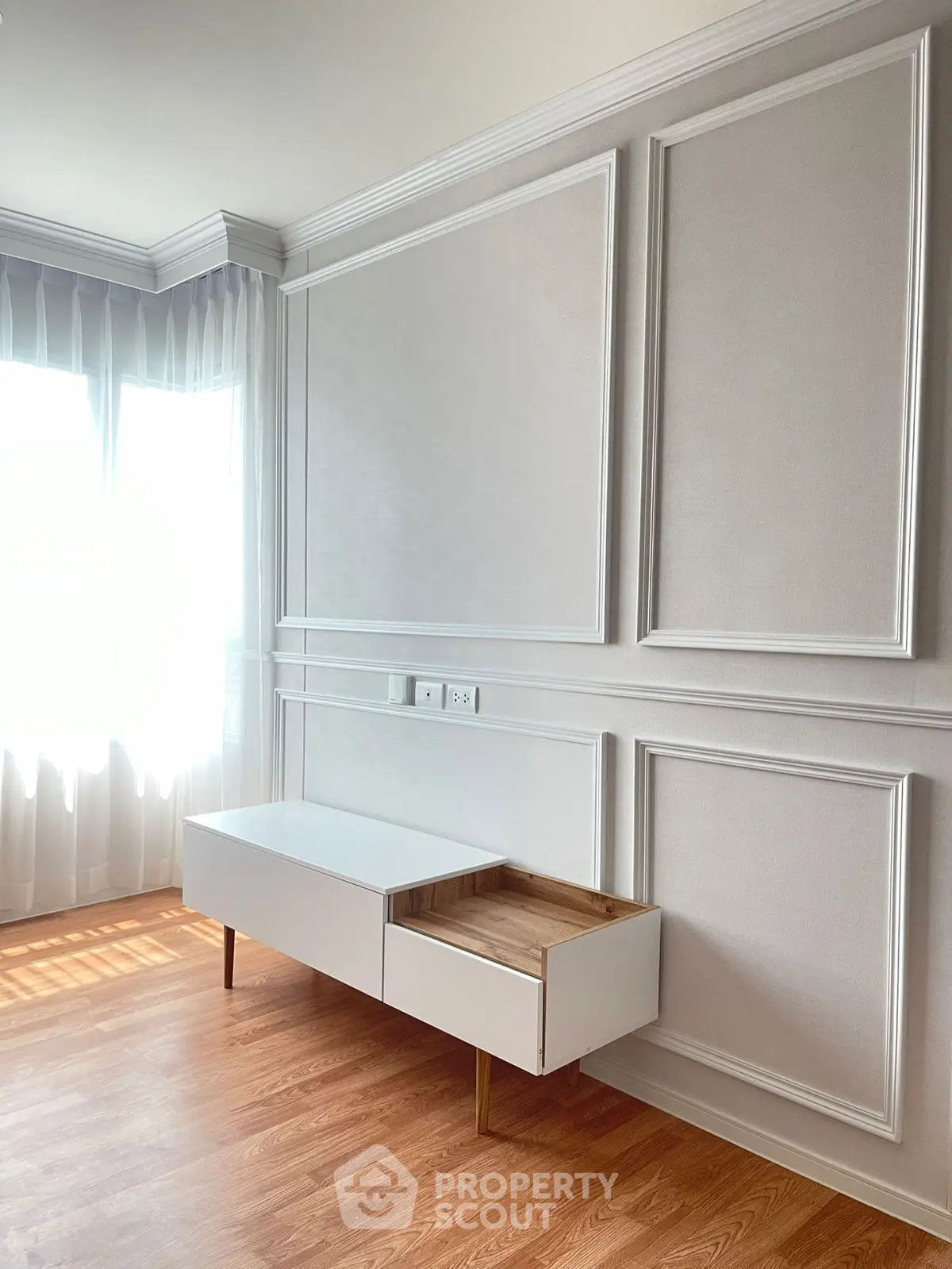 Elegant modern living room with natural light and stylish wall paneling