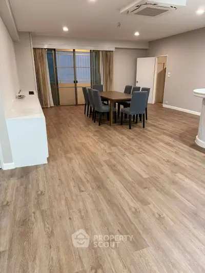 Spacious dining area with elegant wooden flooring and modern furniture, perfect for family gatherings.