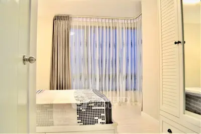 Bright and cozy bedroom with large window and stylish curtains, perfect for relaxation.