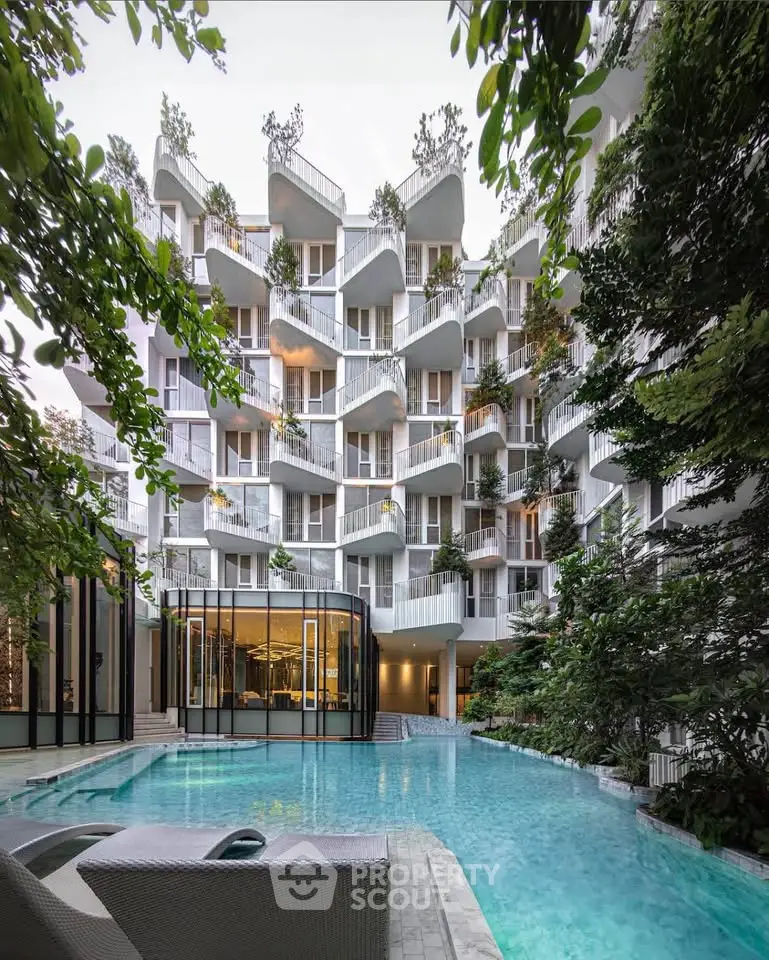 Luxurious modern apartment building with unique balconies and stunning pool area surrounded by lush greenery.
