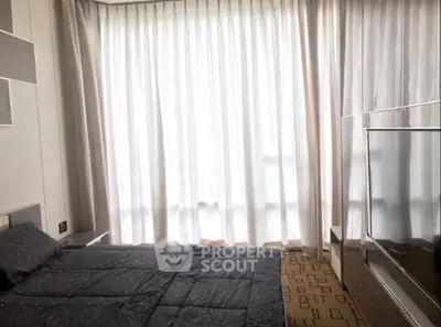 Modern bedroom with large window and elegant curtains in a stylish apartment.