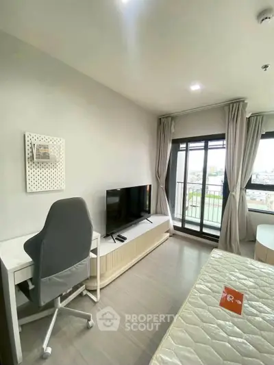 Modern bedroom with balcony view, sleek furniture, and natural light.