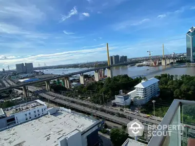 Stunning cityscape view from a high-rise balcony overlooking river and bridge.