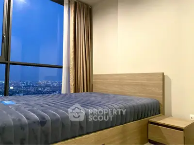 Modern bedroom with city view, featuring a cozy bed and elegant curtains, perfect for urban living.