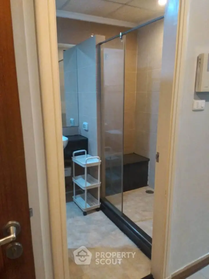 Modern bathroom with glass shower enclosure and sleek tile flooring.