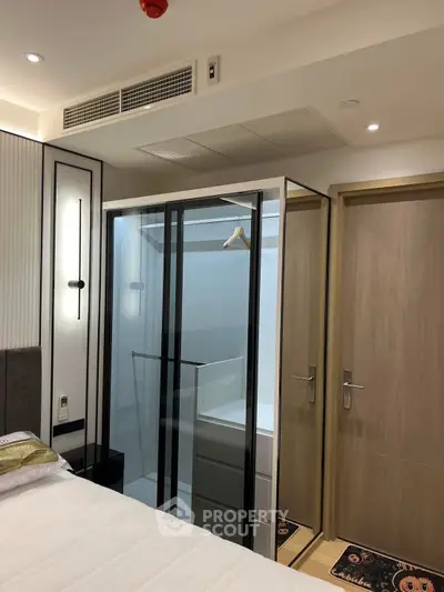Modern bedroom with glass-enclosed closet and elegant lighting