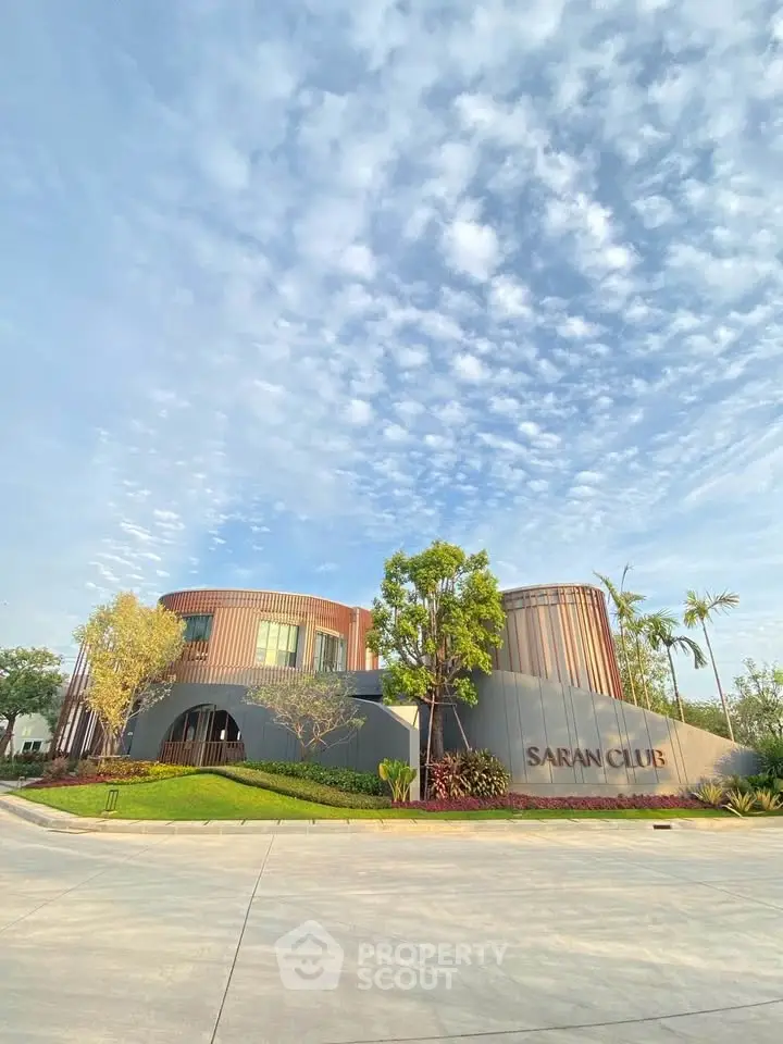 Stunning modern building exterior with unique architectural design and lush landscaping under a clear blue sky.
