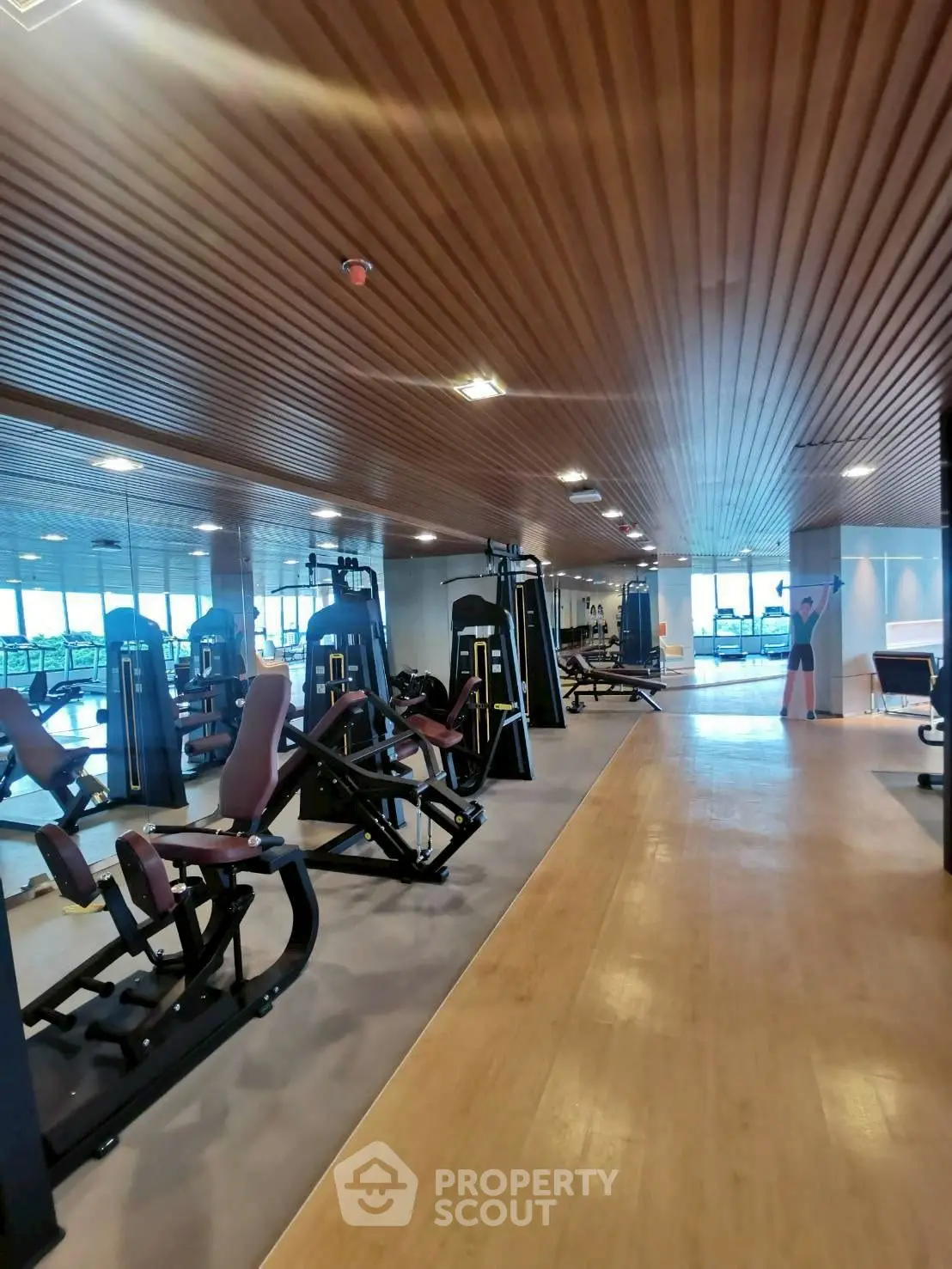 Spacious modern gym with state-of-the-art equipment and wooden ceiling design