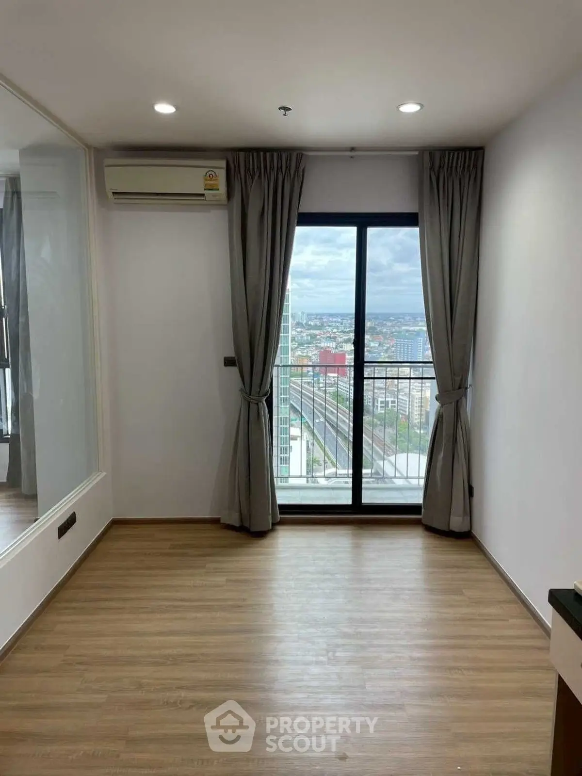 Spacious room with large window offering stunning city view, perfect for modern living.