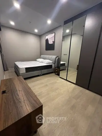 Modern bedroom with sleek design, featuring a stylish bed, mirrored wardrobe, and elegant wooden furniture.