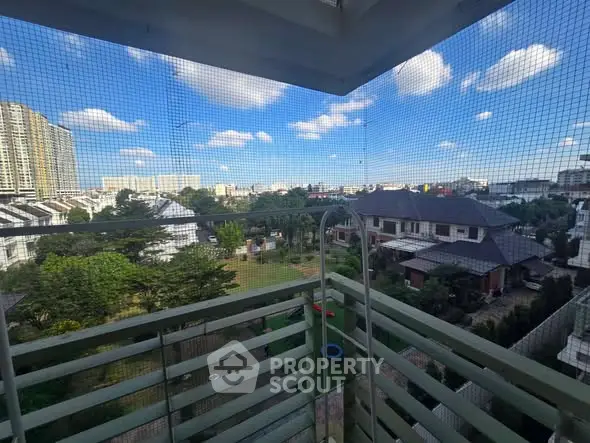 Stunning balcony view overlooking a lush garden and cityscape under a clear blue sky.
