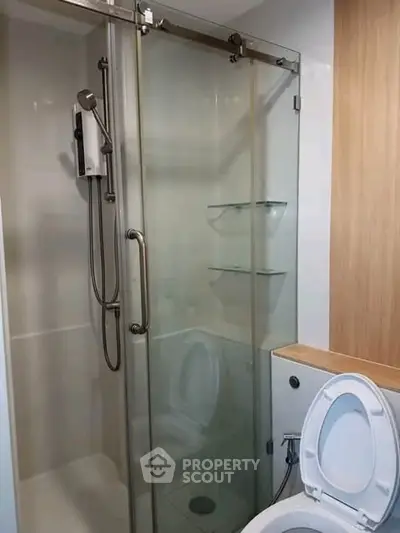 Modern bathroom with glass shower enclosure and toilet, featuring sleek fixtures and minimalist design.