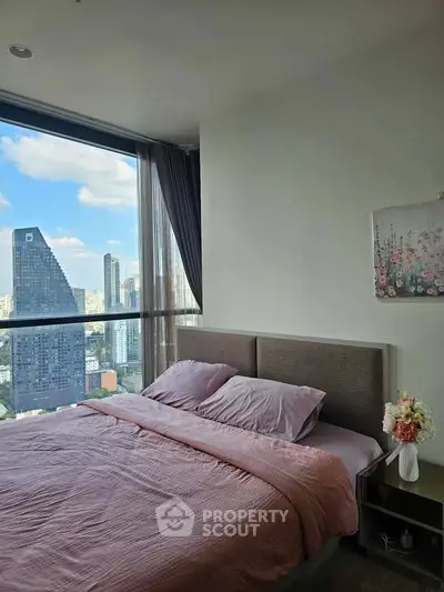 Luxurious bedroom with stunning city view and modern decor in high-rise apartment.