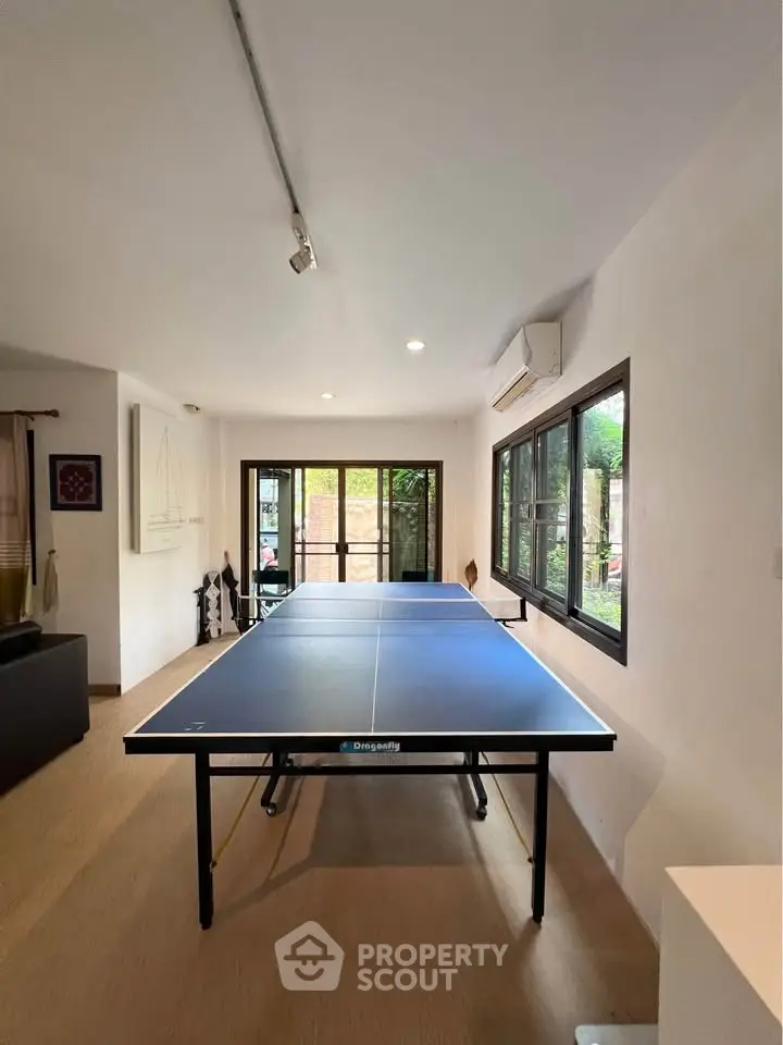 Spacious living area with table tennis setup and large windows for natural light.