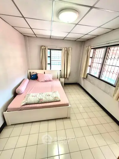 Cozy bedroom with tiled floor and natural light from large windows.
