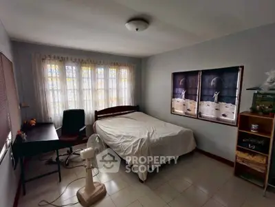 Cozy bedroom with natural light, desk, and bed, perfect for comfortable living.