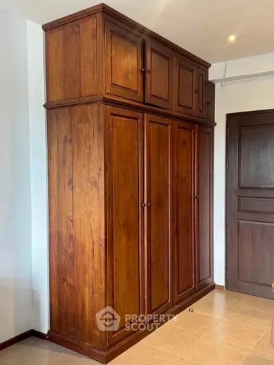 Spacious wooden wardrobe in a modern bedroom with elegant design and ample storage space.