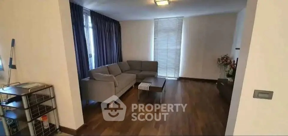 Spacious living room with modern sofa and wooden flooring in a cozy apartment.