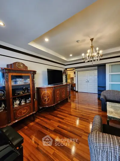 Elegant living room with polished wooden floors, classic furniture, and a chandelier for a luxurious touch.