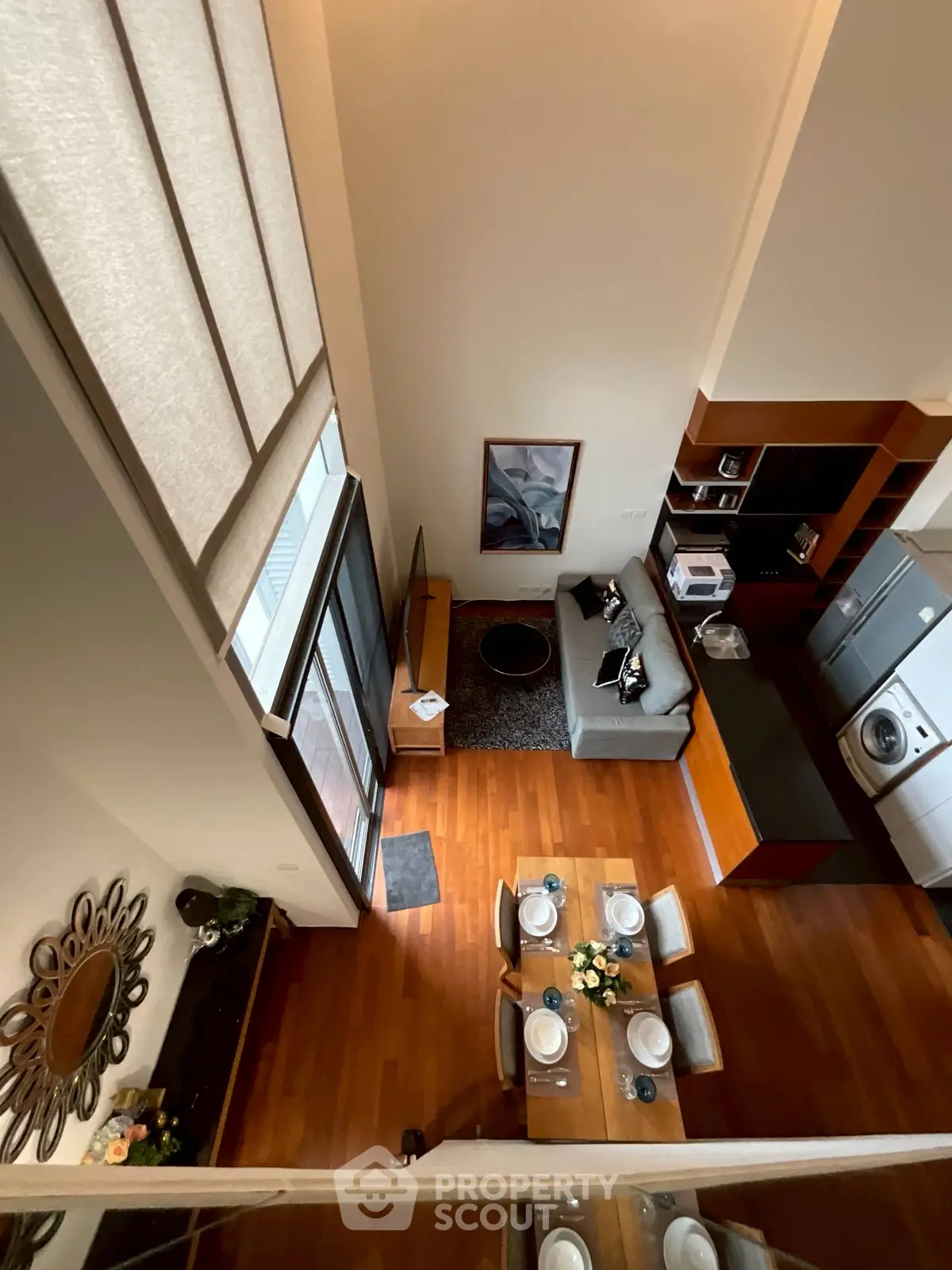 Stunning open-layout living room with modern kitchen and dining area, featuring high ceilings and elegant decor.