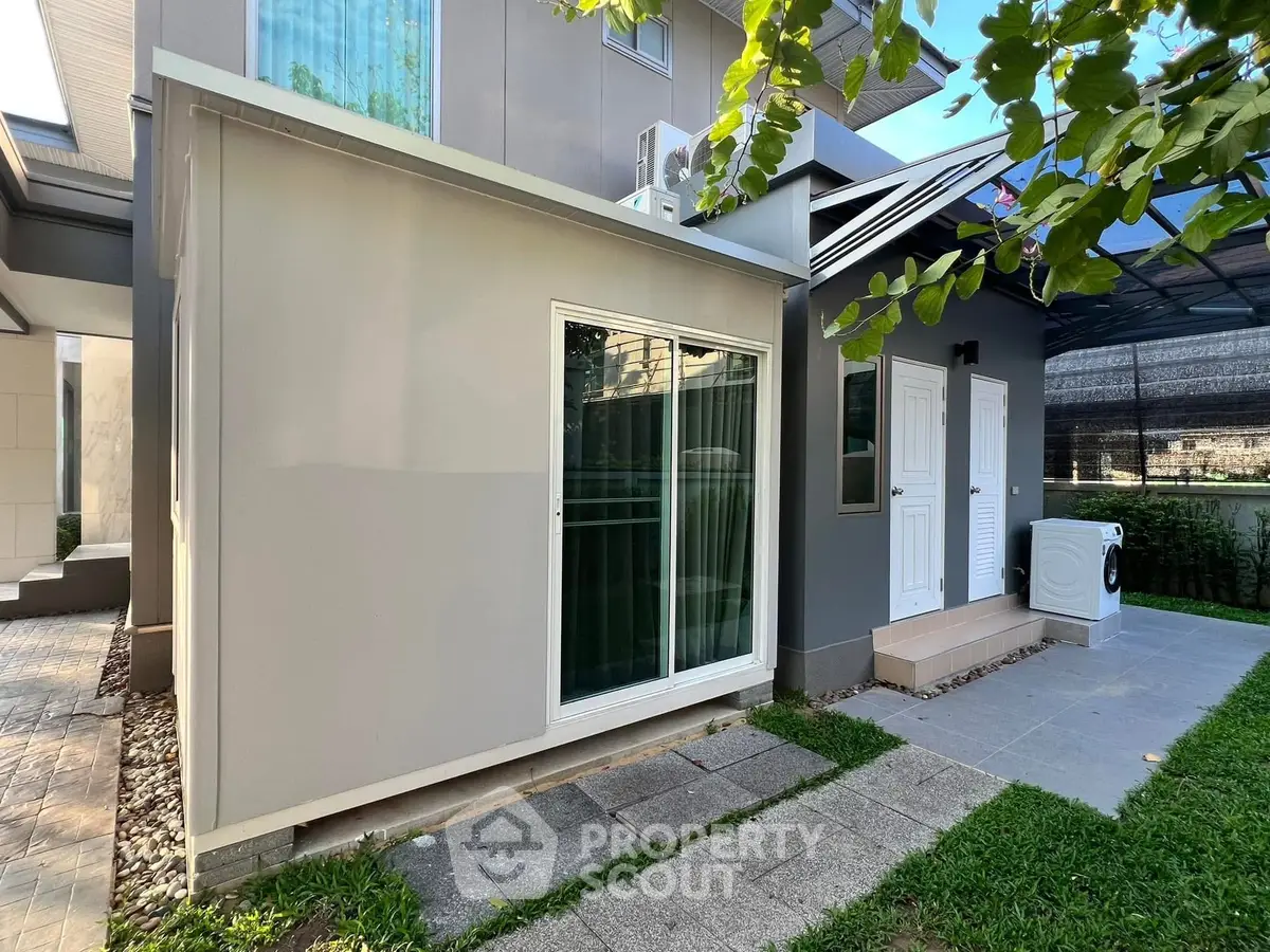 Modern exterior view of a stylish home with sliding glass doors and a washing machine on the patio.