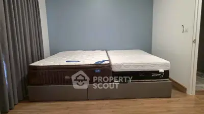 Spacious bedroom with two large mattresses on a modern bed frame, featuring elegant curtains and wooden flooring.