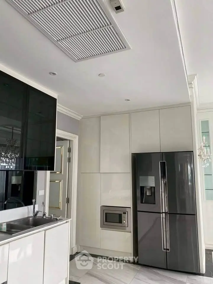 Modern kitchen with sleek cabinetry, built-in microwave, and stainless steel fridge.