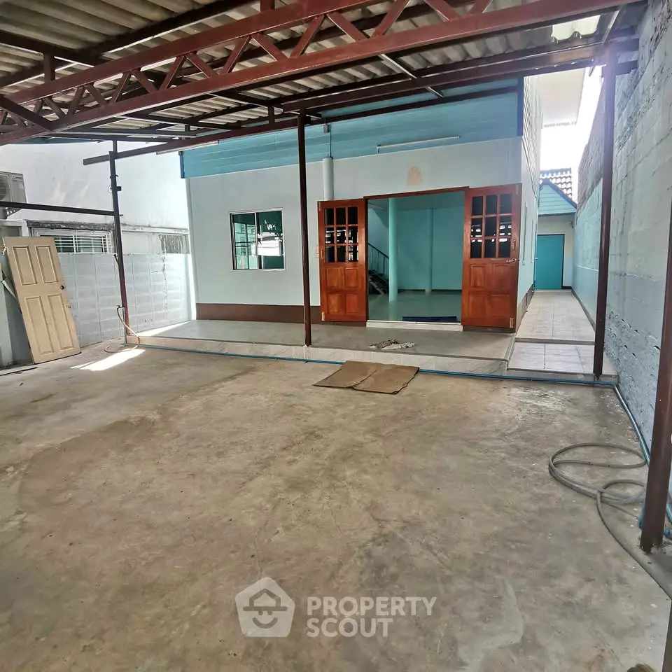 Spacious covered outdoor area with tiled entrance and wooden doors, ideal for versatile use.