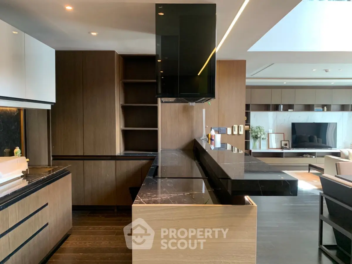 Luxurious modern kitchen with sleek black countertops and open layout adjacent to stylish living room.