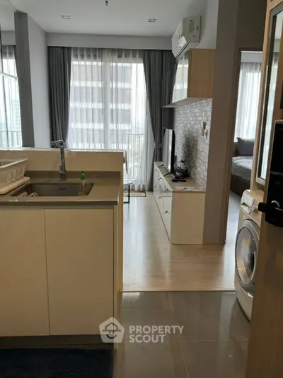 Modern apartment interior with open kitchen and living room, featuring sleek design and natural light.