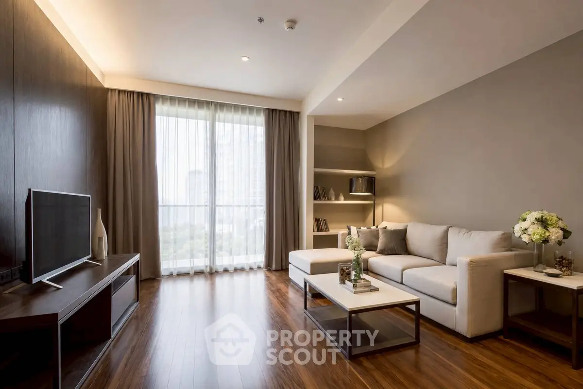 Elegant living room with modern decor, large window, and cozy seating area in a stylish apartment.