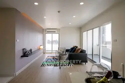 Modern living room with sleek design and large windows opening to a balcony with city views.