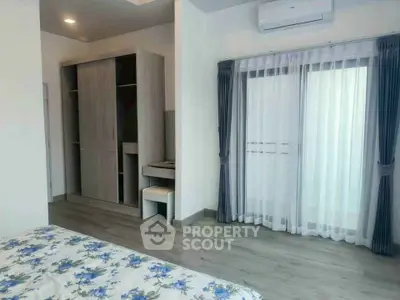 Spacious bedroom with modern wardrobe and large window for natural light.