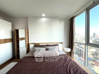 Modern bedroom with large windows offering stunning city views and ample natural light.