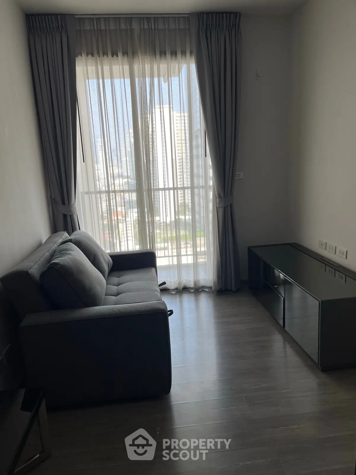 Modern living room with city view, featuring a cozy sofa and sleek entertainment unit.