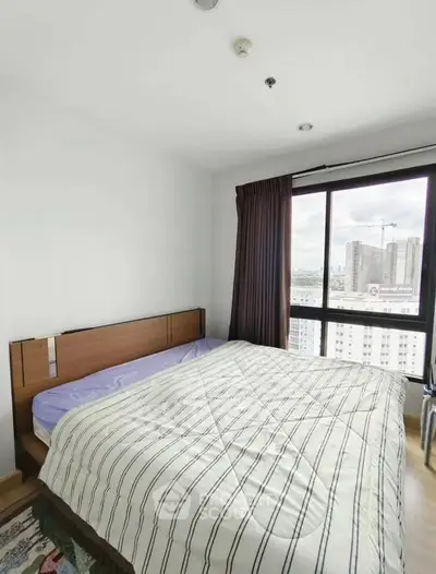 Cozy bedroom with large window offering city view, featuring a comfortable bed and modern decor.