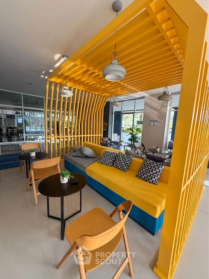 Modern lounge area with vibrant yellow accents and stylish seating in a contemporary building.