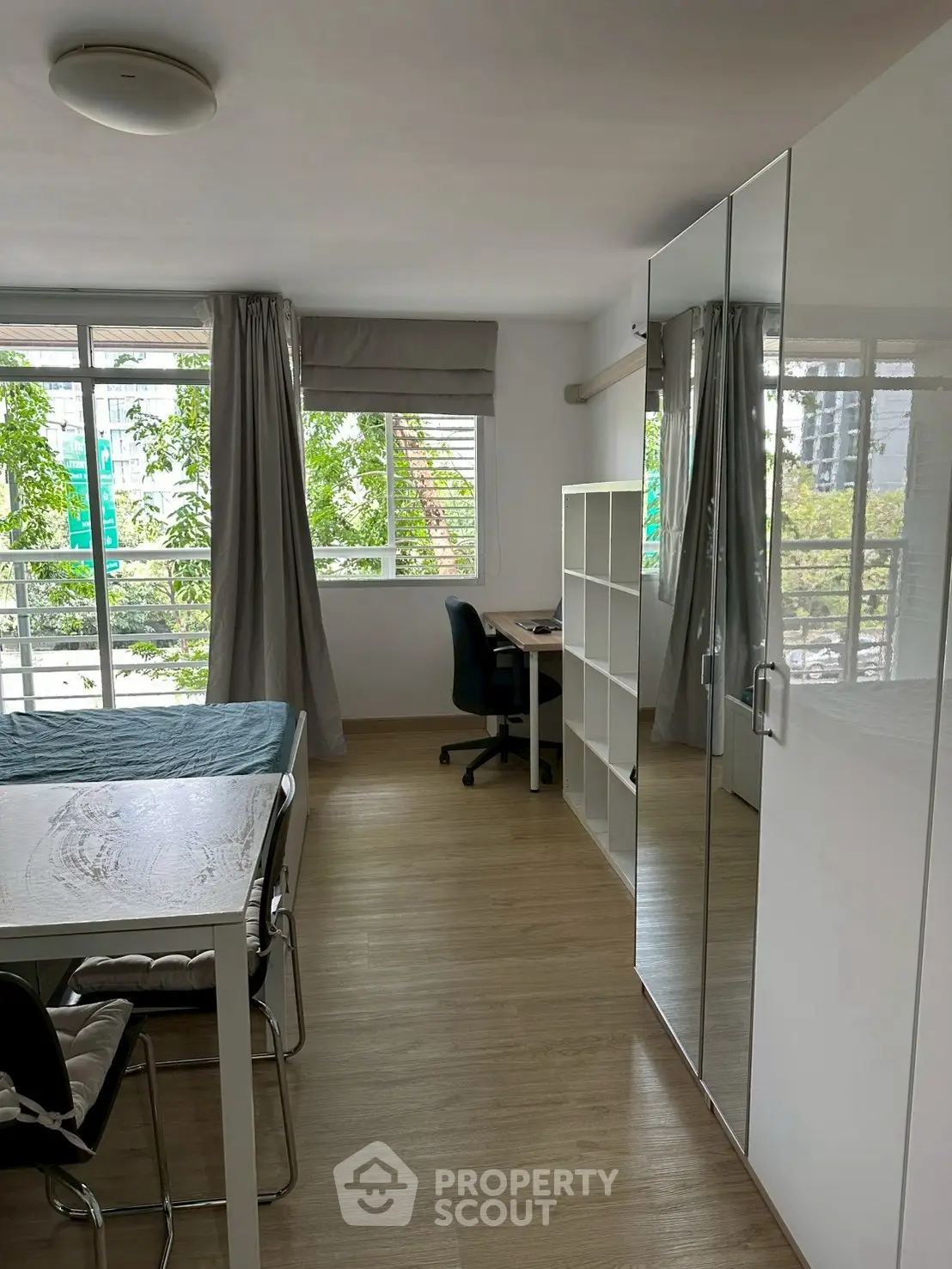 Modern apartment interior with mirrored wardrobe and study area, featuring large windows and stylish decor.