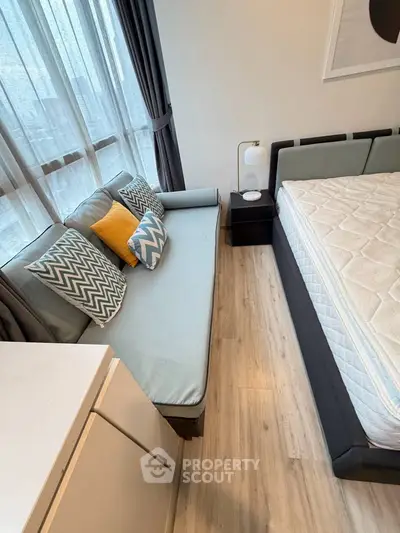 Modern bedroom with stylish sofa and large window, featuring cozy decor and natural light.