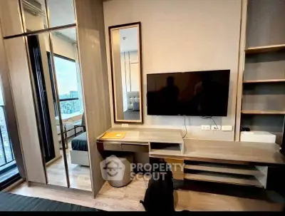 Modern bedroom with built-in desk, TV, and mirrored wardrobe in a stylish apartment.