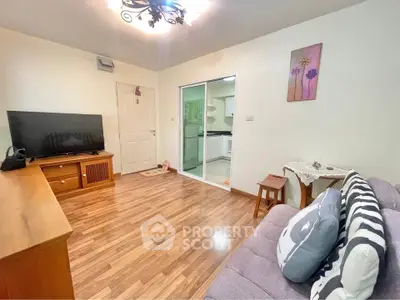 Cozy living room with wooden flooring and modern decor, featuring a large TV and comfortable seating.