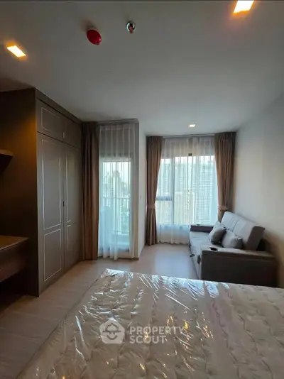 Modern bedroom with large windows and cozy seating area, perfect for relaxation and comfort.
