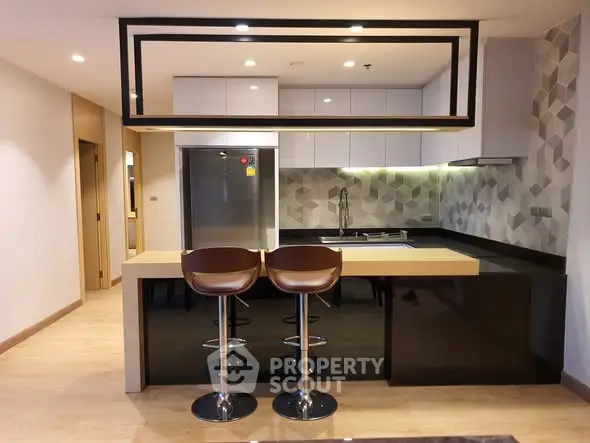 Modern kitchen with sleek design, featuring a breakfast bar and stylish bar stools, perfect for contemporary living.