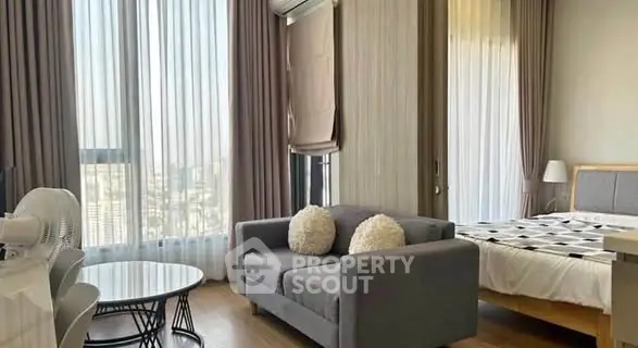 Modern studio apartment with stylish decor and large windows offering city views.