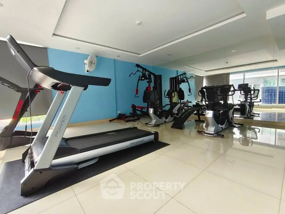 Modern gym with state-of-the-art fitness equipment and mirrored walls in a luxury building.