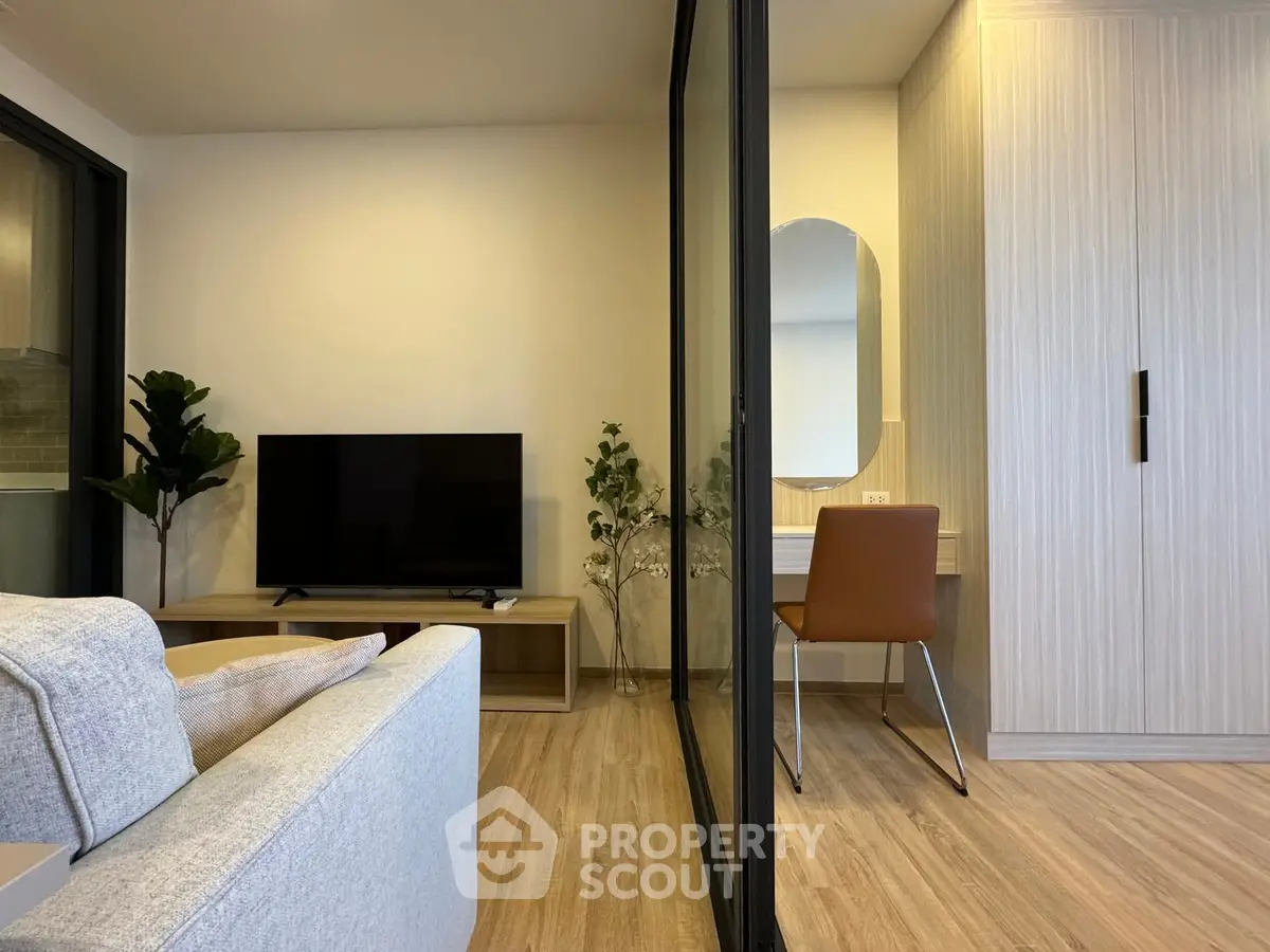 Modern living room with sleek design and cozy workspace, featuring a stylish TV setup and elegant decor.