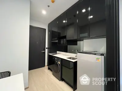 Modern kitchen with sleek black cabinets and appliances in a compact layout