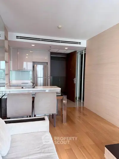 Modern open-layout kitchen with sleek appliances and wooden flooring in a stylish apartment.