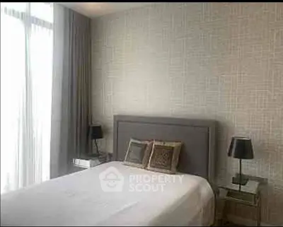 Elegant bedroom with modern decor and natural light, featuring stylish lamps and a cozy bed.